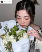 Woman with eyes closed, smelling a bouquet of white roses and daisies.