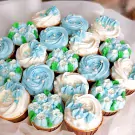 A bouquet of 19 blue, white, and green frosted cupcakes arranged like flowers.
