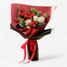 White and red roses, gerberas, and pine in a festive bouquet wrapped in red and black paper with a red ribbon.