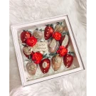 Box of chocolate-dipped strawberries with red flowers and gold embellishments.
