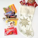 White Christmas stocking filled with candy, including Kit Kat, Snickers, Mars, and Maltesers.
