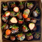 A box of 25 chocolate-covered strawberries, many with sprinkles and some halved to show fruit.