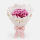 Bouquet of pink mums in white paper with a pink ribbon bow.