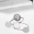 Oval moissanite engagement ring with a halo of small diamonds on a white gold plated sterling silver band.