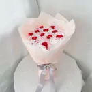 Bouquet of pink, red, and white roses with diamond accents, wrapped in sheer pink paper and tied with a grey ribbon.