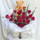 Teddy bear and red roses arranged with a large white bow, for a romantic gift.