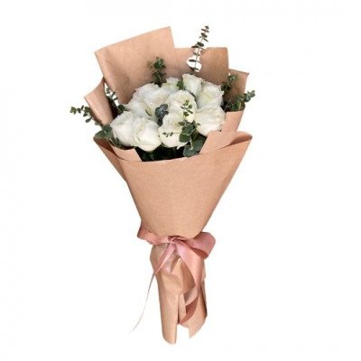 Bouquet of 12 white roses and eucalyptus leaves wrapped in brown paper, tied with a pink ribbon.