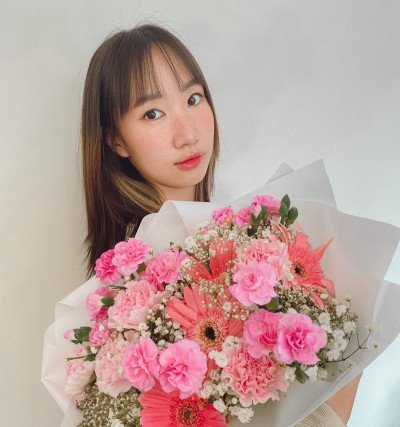 Young woman holding a large bouquet of pink and coral gerberas and carnations.