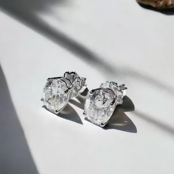 Pair of oval-cut moissanite diamond earrings with silver settings on a white surface.