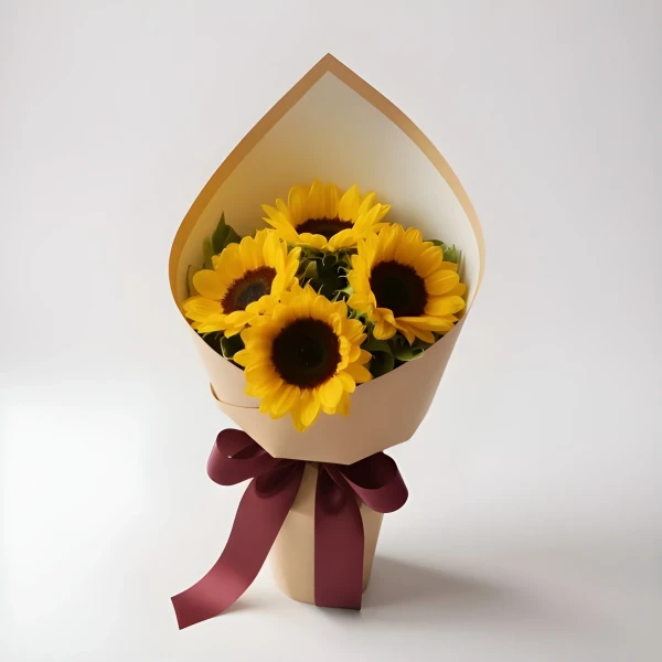 Bouquet of four bright yellow sunflowers with dark centers, wrapped in brown and cream paper and tied with a burgundy ribbon.