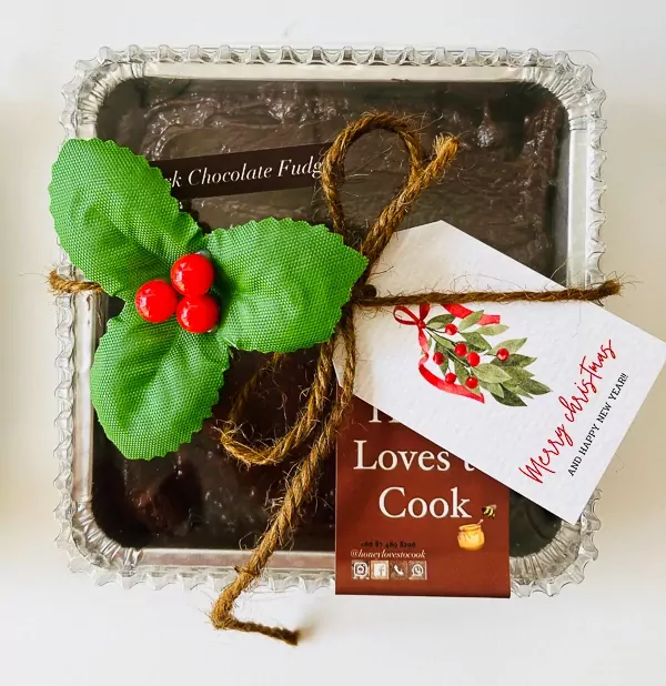 Festive 4x4 inch homemade Christmas fudge in a silver tin, tied with twine and holly.