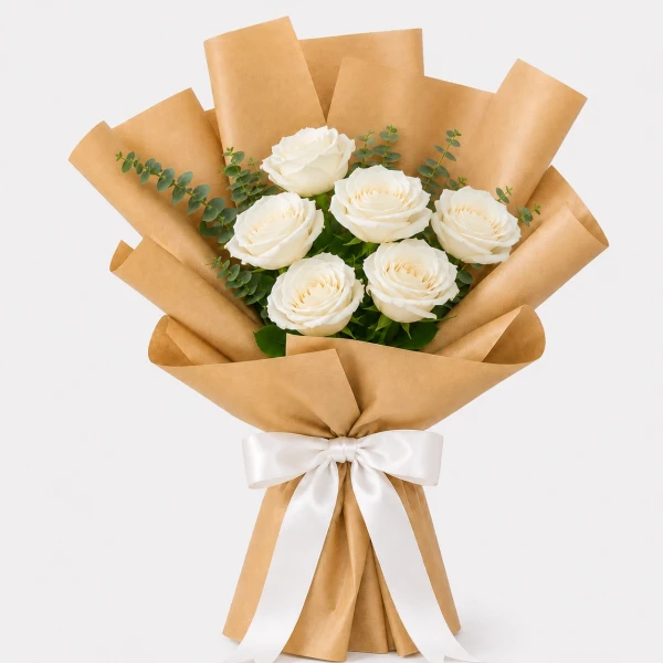 A bouquet of white roses with greenery wrapped in brown paper and tied with a white ribbon.