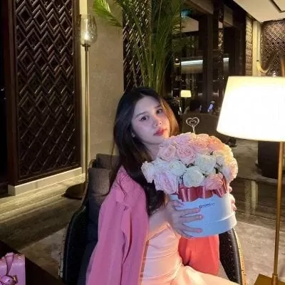 Woman holding a pastel pink and white rose box with a pink ribbon.