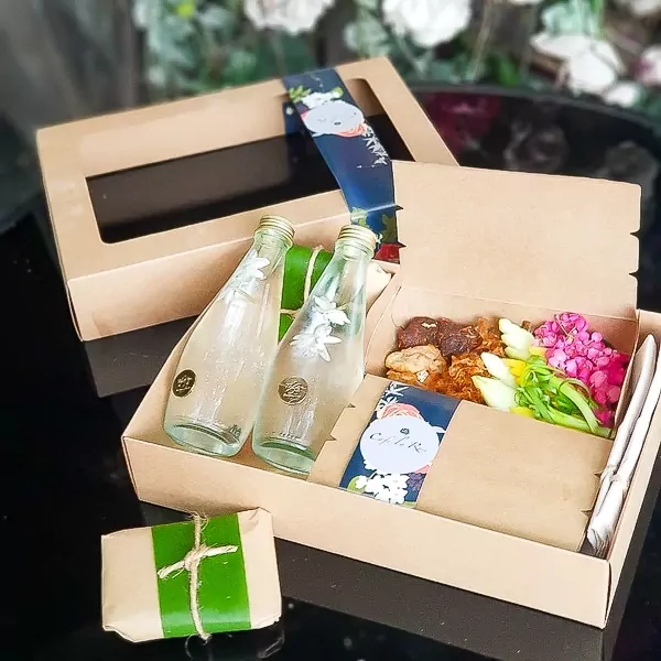 Two bottles of jasmine water and two Thai Khao Chae meals in a paper box set for two people.