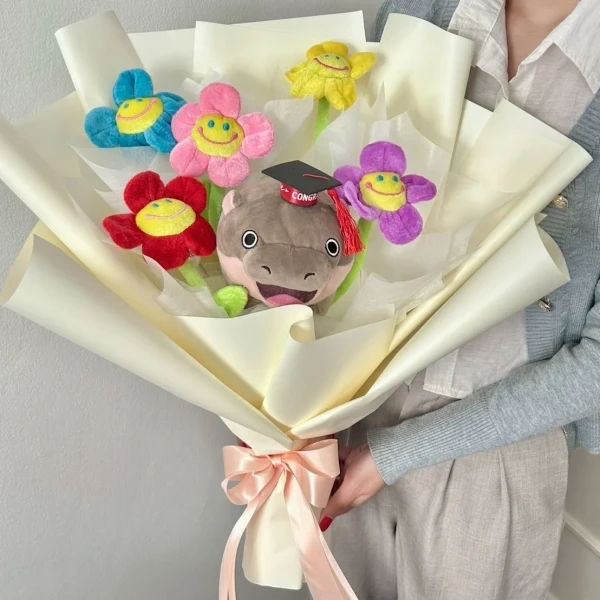 Plush graduation bouquet with a Moodeng character in a cap and smiling flowers.