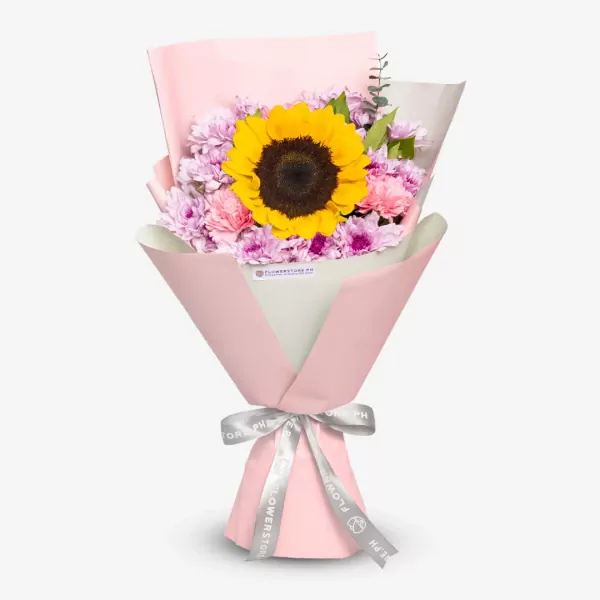 Bouquet of a sunflower surrounded by pink and violet flowers, wrapped in pink paper with a silver ribbon.