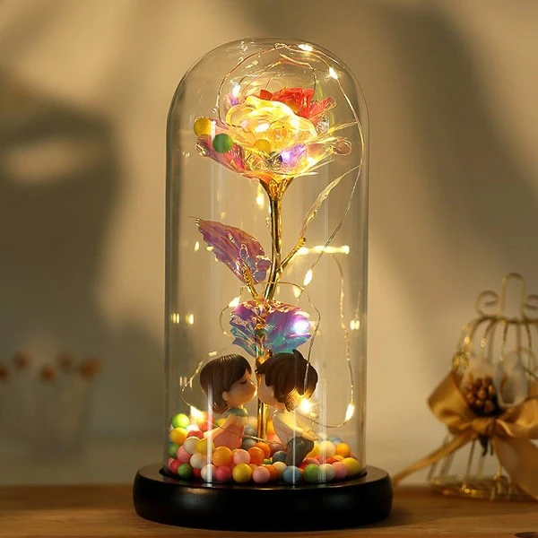 Glass dome with a holographic rose and kissing couple figurines, illuminated by fairy lights.