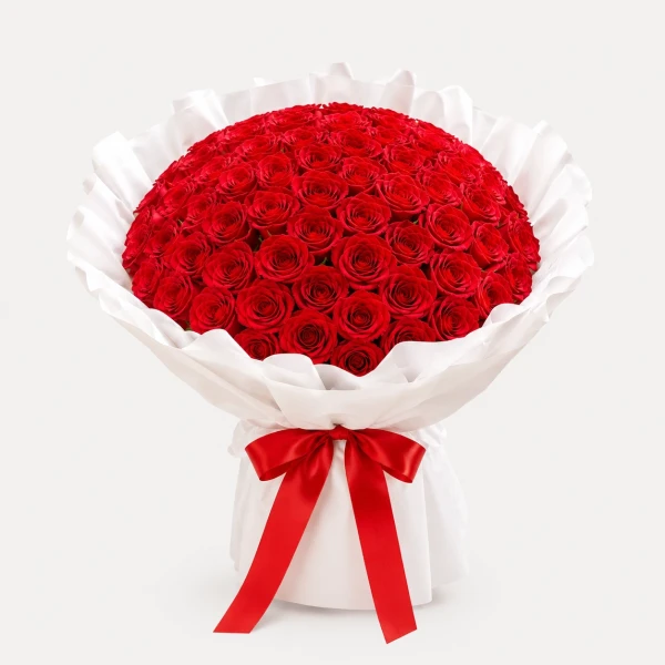 A large bouquet of 99 vibrant red roses, wrapped in white paper and tied with a red ribbon.