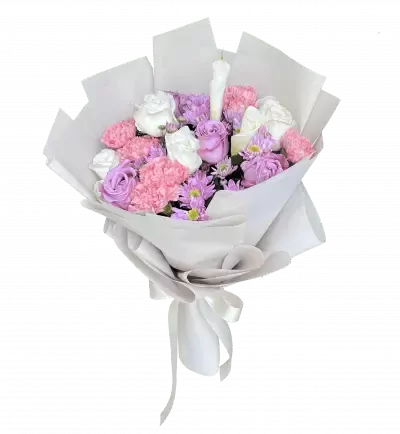 Bouquet of pink and purple roses, white roses, purple mums, and pink carnations with a white candle, wrapped in white paper and tied with a white ribbon.