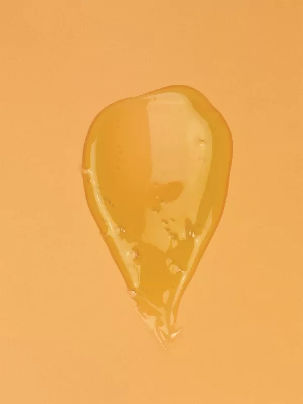 Golden, viscous liquid, like honey or serum, on an orange background.