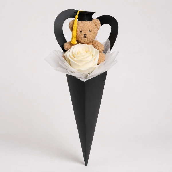 Graduation teddy bear in a black cone with a white rose and black heart-shaped accent.