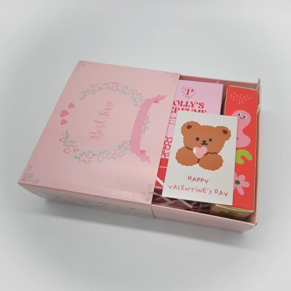 Pink gift box with floral wreath, teddy bear Valentine's card, and perfume bottles.