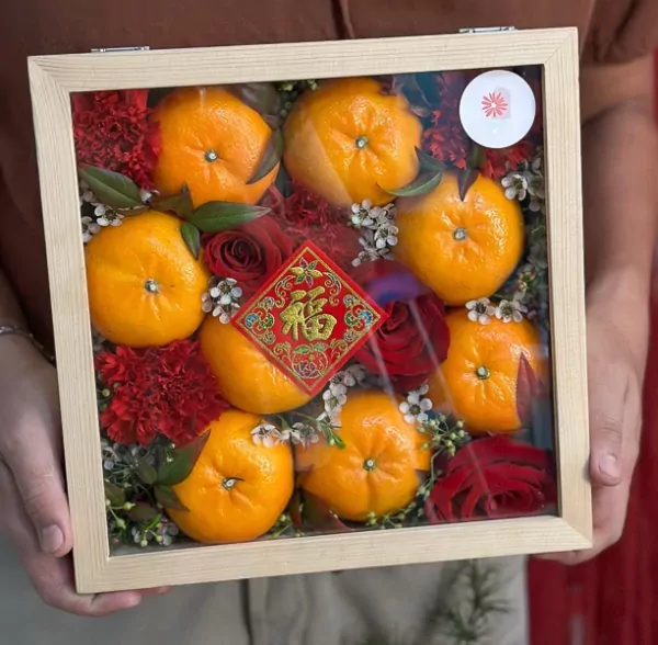 Chinese New Year box with 8 oranges, red roses, carnations, and a "Fu" decoration.