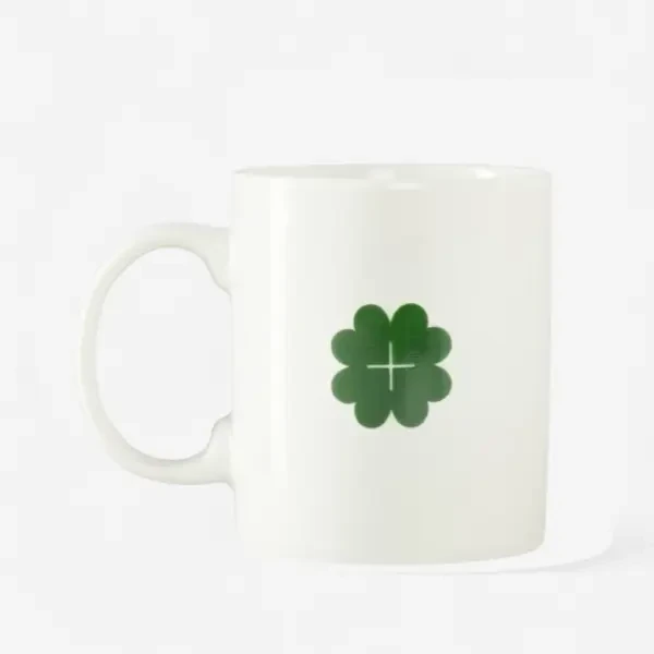 White mug with a green clover and a cross design.