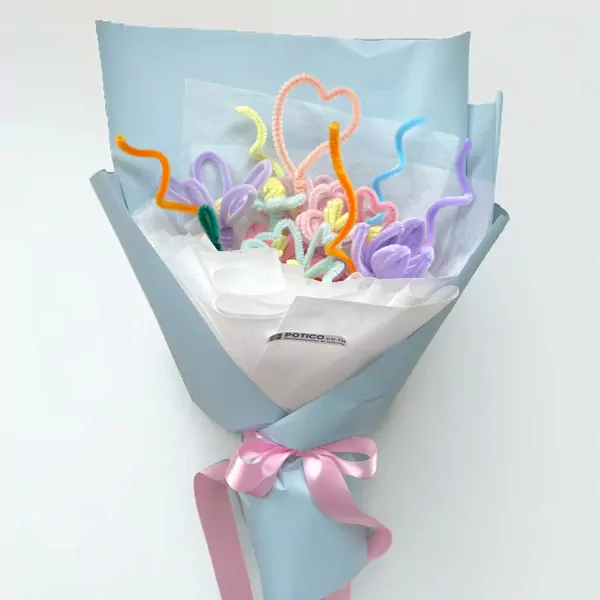 A bouquet of colorful velvet wire flowers and hearts wrapped in light blue paper and tied with a pink ribbon.