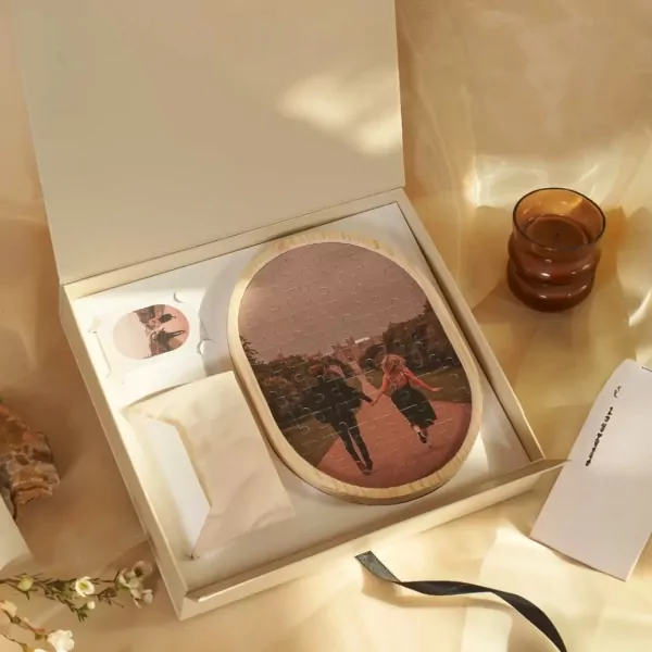 Oval jigsaw puzzle with a couple's photo in an open gift box with a candle.