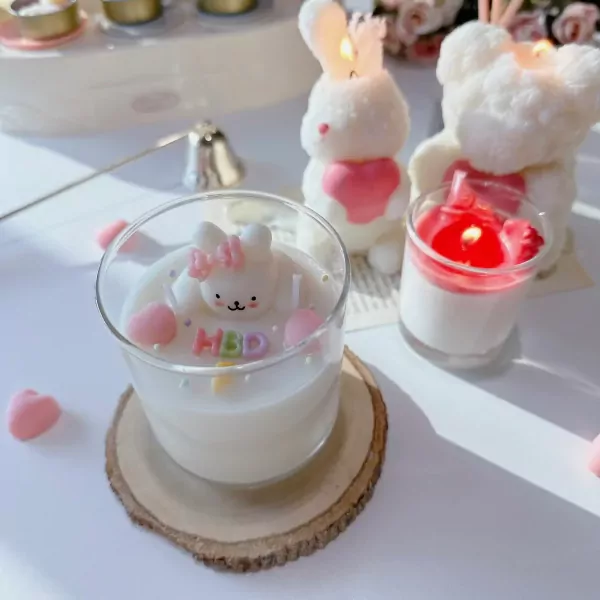 Candle in a glass with a white rabbit, pink bow, and "HBD" letters.