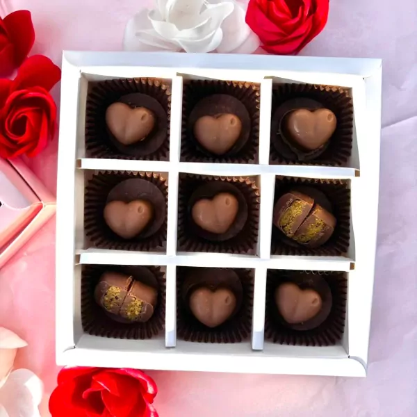 Box of 9 heart-shaped Dubai chocolates, some filled with pistachios, surrounded by red and white roses.