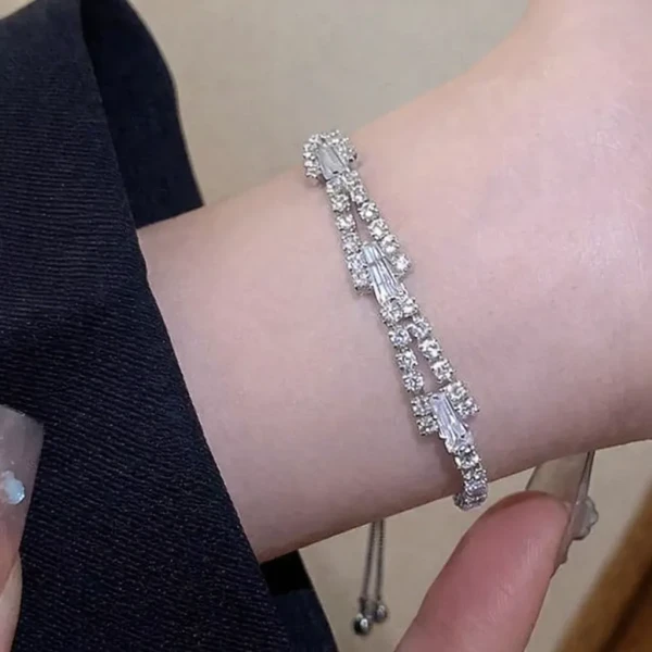A silver bracelet with baguette-cut and round rhinestones on a wrist.
