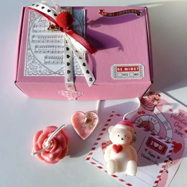 Pink gift box with a teddy bear candle, rose candle, heart candle, and Valentine's game card.