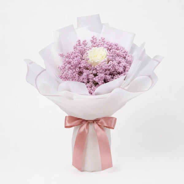 Bouquet of pink limonium with one white rose, wrapped in white paper and tied with a red bow.