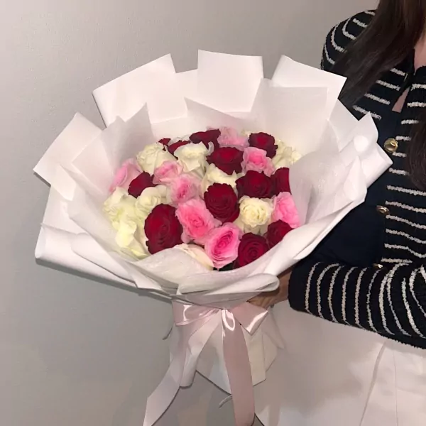 Bouquet of 30 white, pink, and red roses wrapped in white paper, tied with a light pink ribbon.