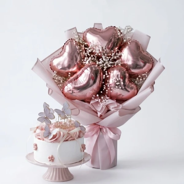 Rose gold heart balloons and a white butterfly cake on a pink stand.