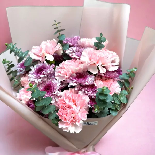 Pink carnations and purple mums arranged in a bouquet with eucalyptus, wrapped in paper.
