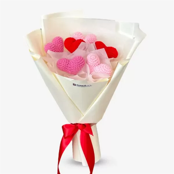 Crocheted pink and red hearts in a bouquet wrapped in white paper and tied with a red ribbon.