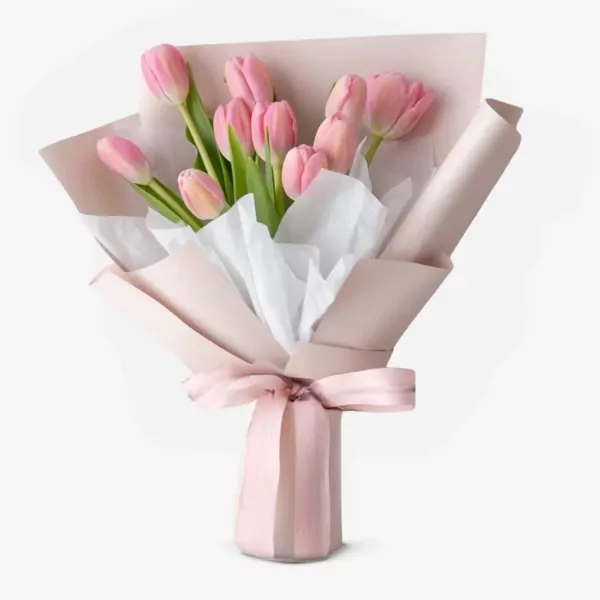 Bouquet of pink tulips with green leaves, wrapped in pink and white paper, tied with a pink ribbon.