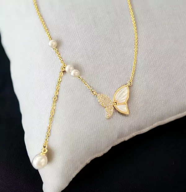 Gold necklace with butterfly pendant, pearls, and diamond accents.