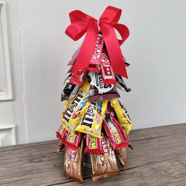 Chocolate Christmas tree made of candy bars and M&Ms, topped with a red bow.