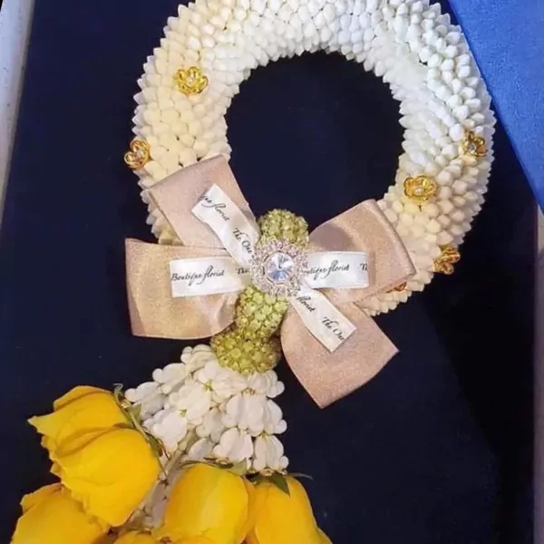 Golden Glow Malai: White flower garland with yellow roses, gold bow, and jeweled center.