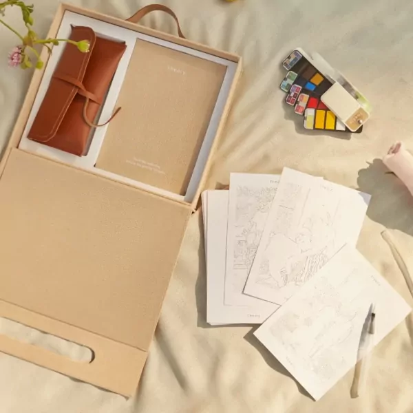 Gift box with custom coloring set, notebook, and tan leather roll.