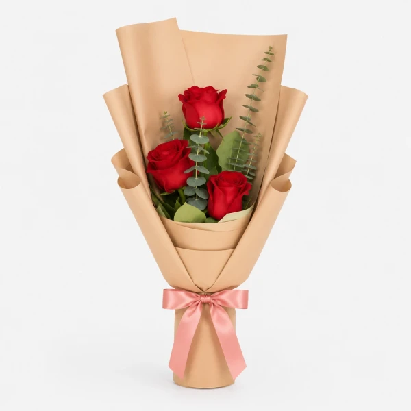 Three red roses wrapped in brown paper with a pink ribbon.