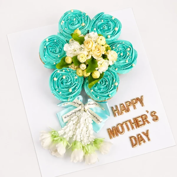 Blue frosted cupcakes arranged as a flower, with real jasmine, malai garland, and "Happy Mother's Day" text.