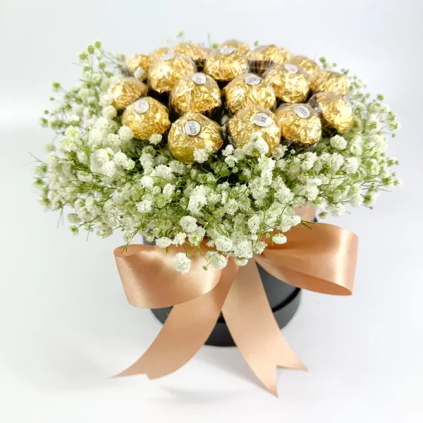 Ferrero Rocher chocolates in a round box with white gypsophila and a tan ribbon bow.