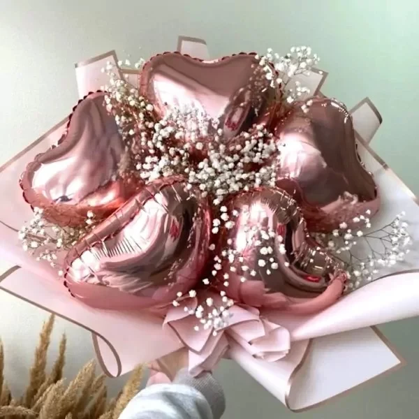 Rose gold heart-shaped balloons with baby's breath in a bouquet.