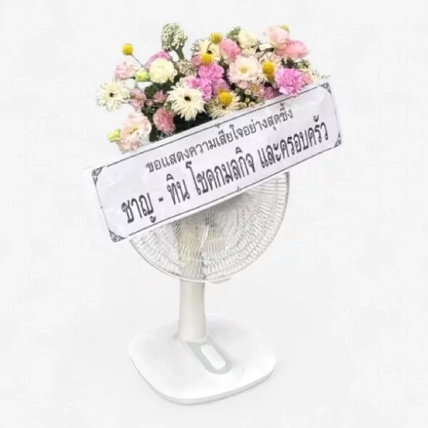 A floral arrangement in a fan shape with a Thai condolence message on a white stand.