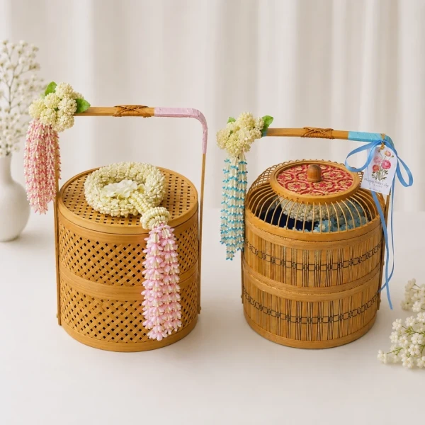 A 2-tier traditional bamboo basket set featuring a delicate garland and artisanal Thai desserts on fresh floral beds